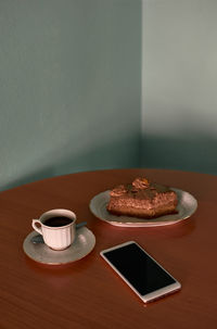 Coffee cup, a cupcake and phone on a corner table. conceptual image