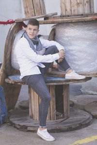 Boy sitting on wooden spool in city