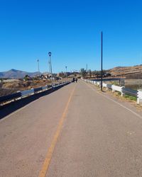 Empty road against clear blue sky
