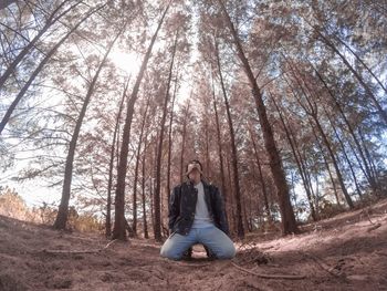 Man kneeling against trees in forest