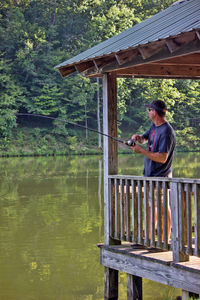 Side view of man using mobile phone by lake