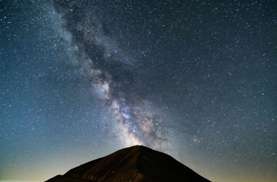 Low angle view of mountain against star field