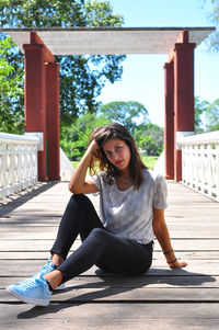 Portrait of young woman sitting on footbridge