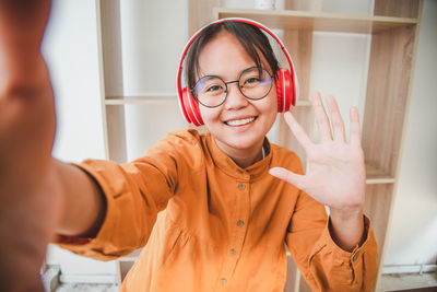 Portrait of smiling girl waving while wearing headphones
