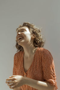 Smiling young woman looking away against gray background