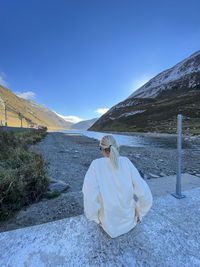 Rear view of woman standing on mountain against sky