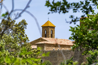 Built structure by trees and building against sky