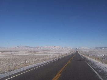 Empty road against clear blue sky