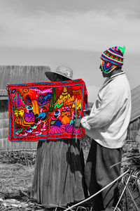 Rear view of woman holding multi colored umbrella against sky