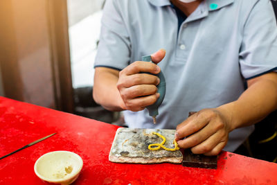 Midsection of man cleaning jewelry 