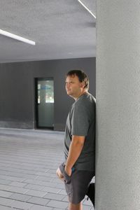 Side view of man leaning on column