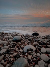 Surface level of stones on beach against sky during sunset