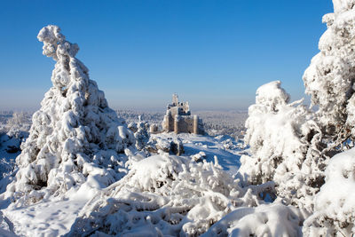 Snow covered built structures against clear blue sky