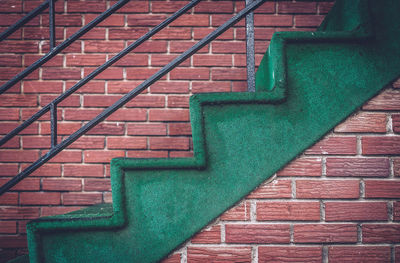 Green staircase against brick wall