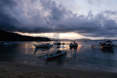 Boats moored on sea against sky during sunset