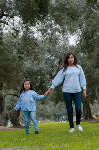 Full length of a smiling girl standing against trees