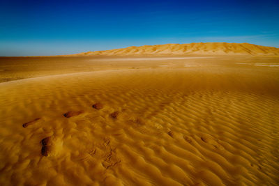 Scenic view of desert against clear blue sky