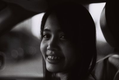 Close-up of smiling young woman in car