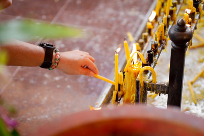 Close-up of hand burning candle