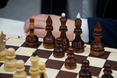 Cropped hand of man by chess pieces on table
