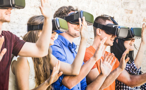 Friends using virtual reality simulators while gesturing against wall