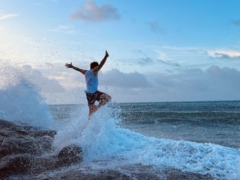 Rear view of man surfing in sea against sky