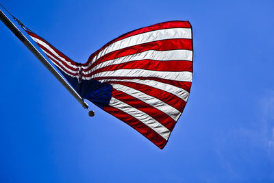 Low angle view of american flag against blue sky