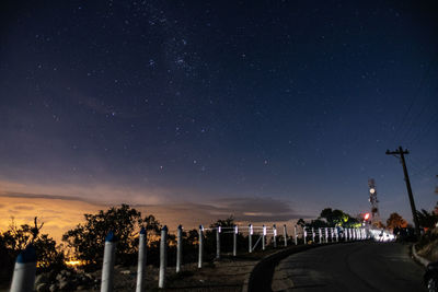 Illuminated street against sky at night