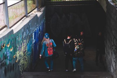 Rear view of people walking in graffiti on wall