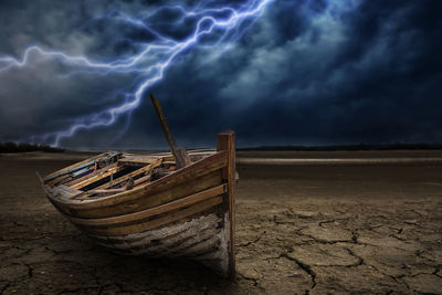 Abandoned boat on beach against sky