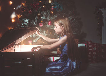 Girl in illuminated christmas tree