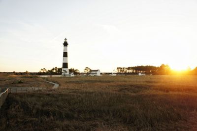 Lighthouse on field at sunset