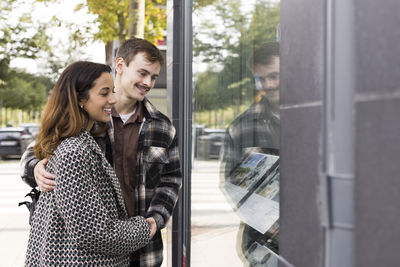 Smiling young couple looking at placard on window