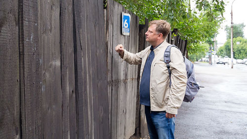 A lost adult male tourist with a backpack knocks closed wooden door.