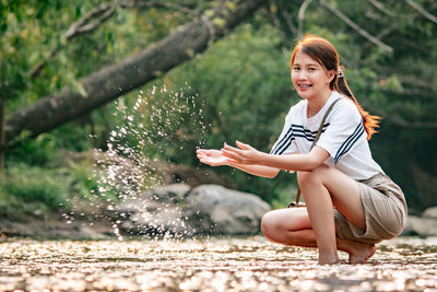 Full length of woman sitting by water