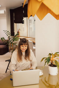 Young woman using digital tablet while sitting at home