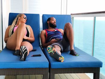 Full length of friends relaxing on deck chairs in ship