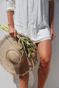 Midsection of woman holding hat standing outdoors