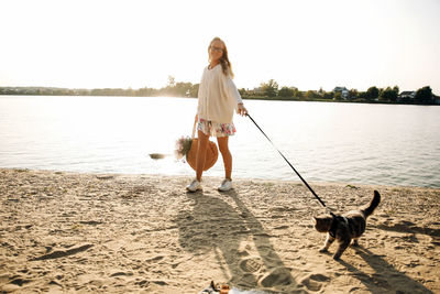 Rear view of woman with dog standing at beach