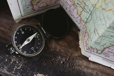 Compass lying on a wooden table next to the map