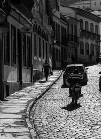 Rear view of man walking on street amidst buildings