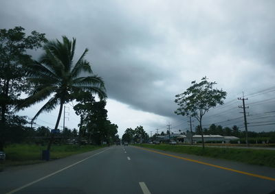 Road by trees against sky