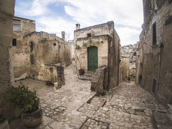 Footpath amidst old buildings against cloudy sky