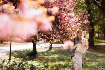 Full length of young man with pink flowers in park