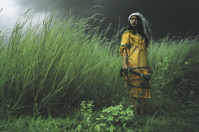 Woman in costume holding axe amidst grass