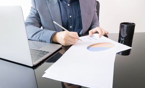 Front view of young and smart businessman manager who is working on work place desk in office 