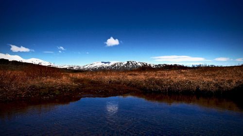 Scenic view of lake and mountains against blue sky