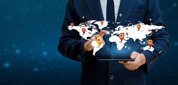 Digital composite image of businessman holding digital tablet with world map