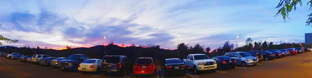 Cars parked in parking lot against cloudy sky