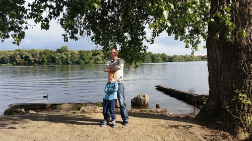 Portrait of father and son with arms crossed standing at lakeshore